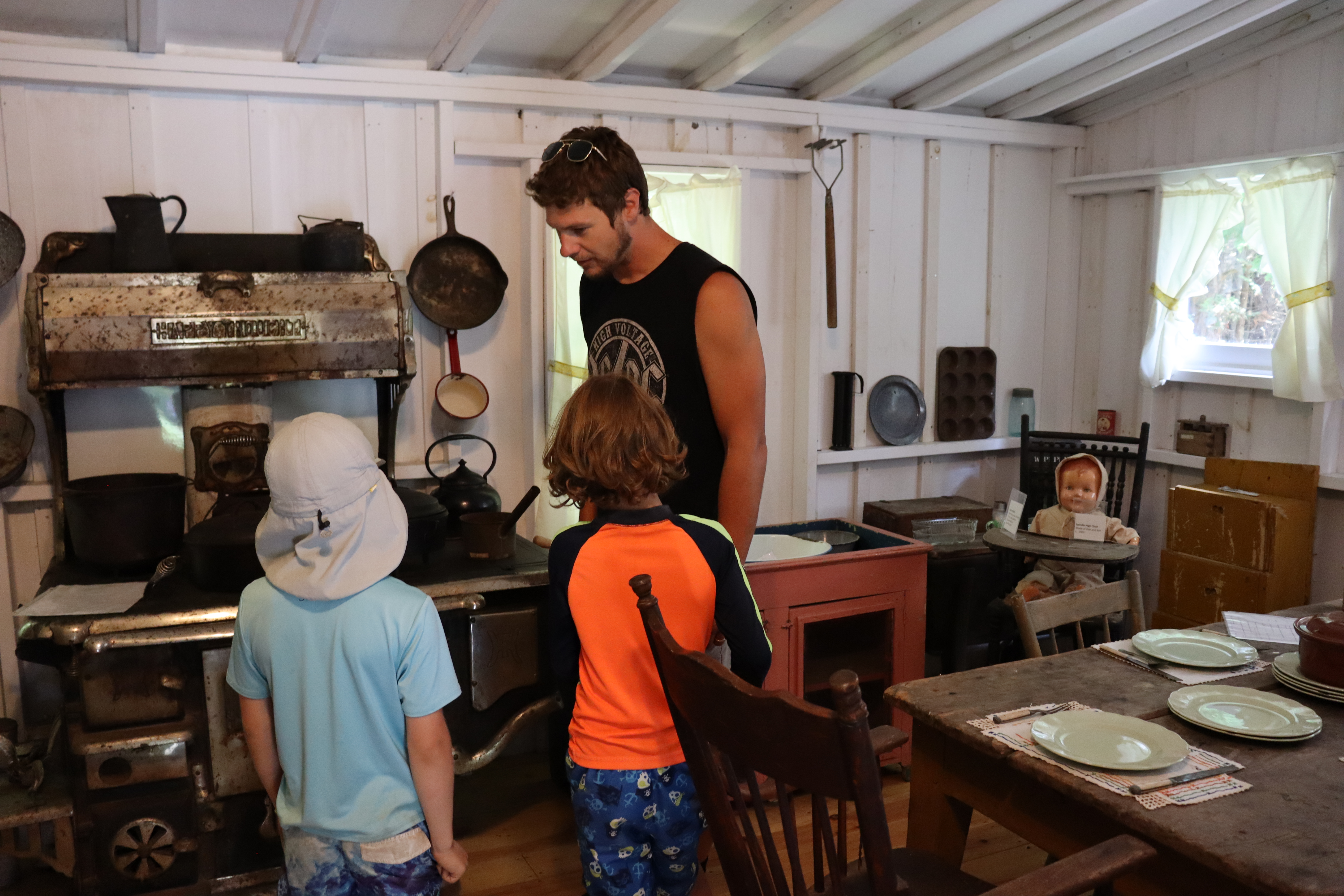 Visitors viewing Belrose Cabin kitchen exhibit with common pioneer homemaking artifacts.