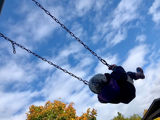 Child on swing with sky backdrop